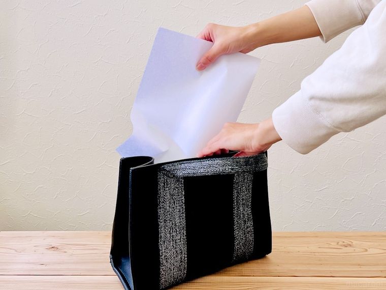 小さいバッグに書類を入れようとしている様子
