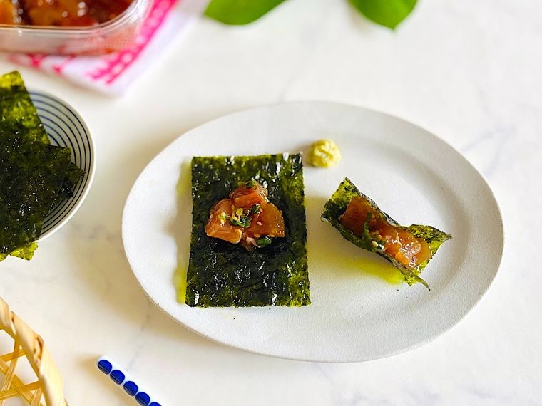 コストコのマグロポキを、グレーの皿の上でわさびと一緒に海苔で巻いているところ