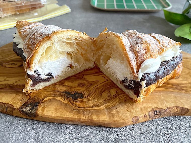 コストコのあんホイップクロワッサンを1個木製のカッティングボードに置いて半分にカットしたところ