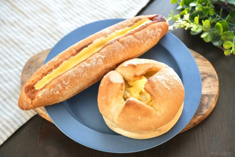 木のカッティングボードと青い皿にのったバターのせポテトフランスパンと明太フランスパンとストライプの布