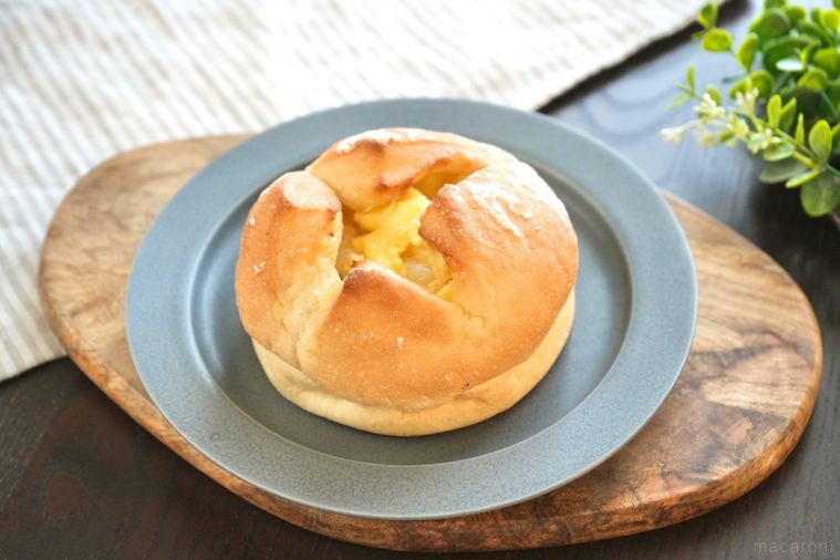 木のカッティングボードとグレーの皿にのったバターのせポテトフランスパンとストライプの布