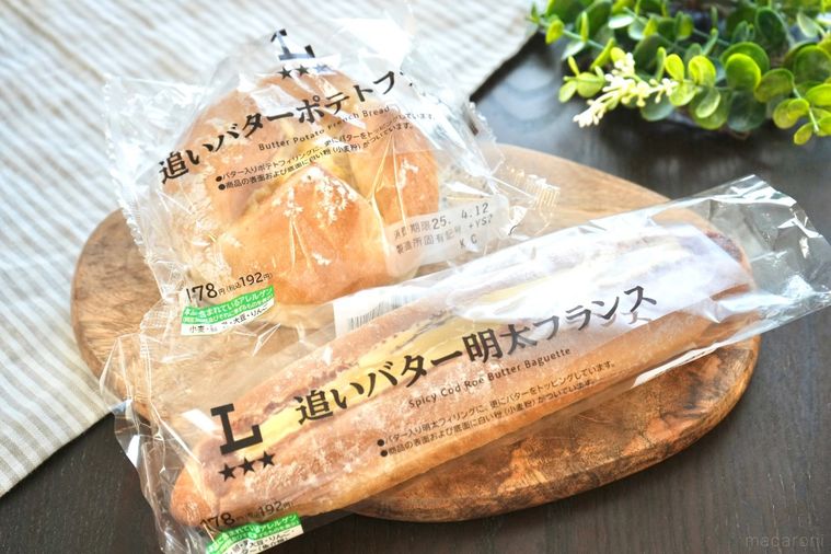 木のカッティングボードと白い皿にのったバターのせのフランスパン
