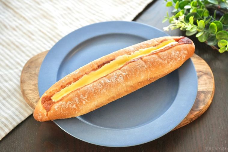 木のカッティングボードと青い皿にのったバターのせ明太フランスパンとストライプの布