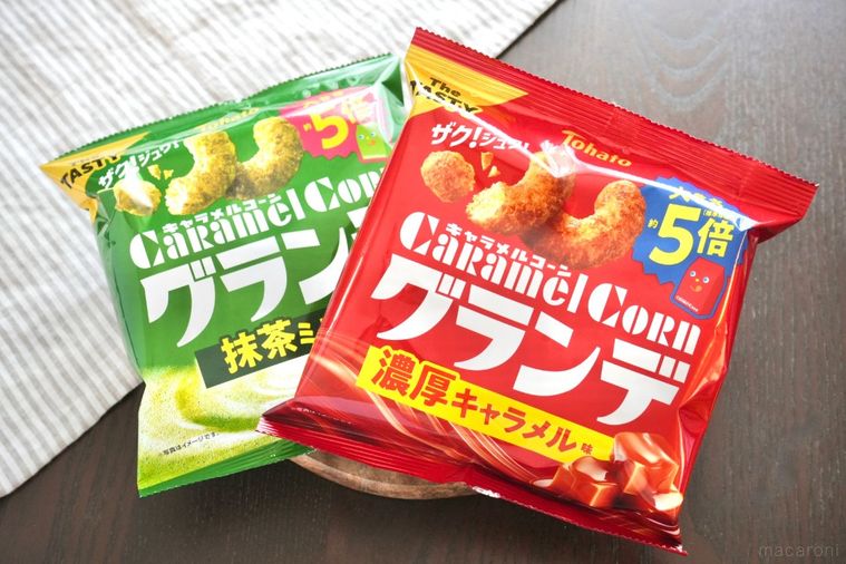 木のカッティングボードにのった緑と赤色のパッケージのキャラメルコーングランデとストライプの布