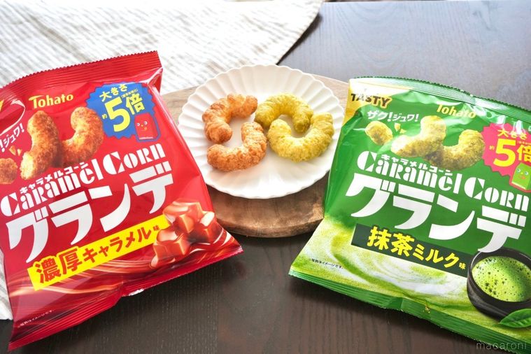 木のカッティングボードと白い皿にのったキャラメルコーングランデと赤と緑色の袋のパッケージとストライプの布