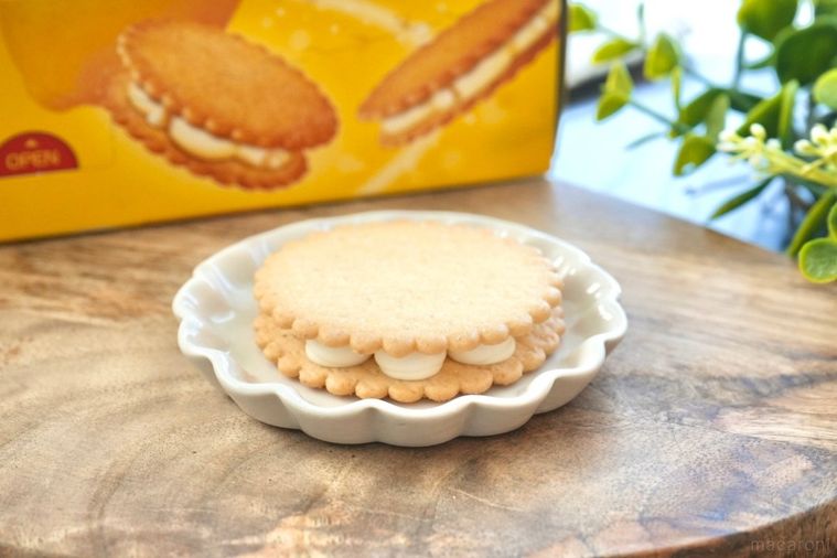 木のカッティングボードと白い皿にのったレモン味のビスケットサンド