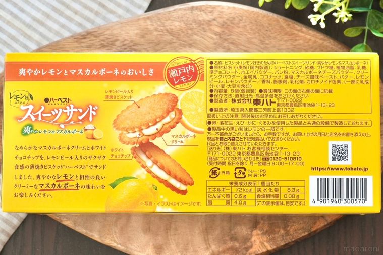 木のカッティングボードにのった黄色い箱のビスケットサンドとストライプの布とグリーン