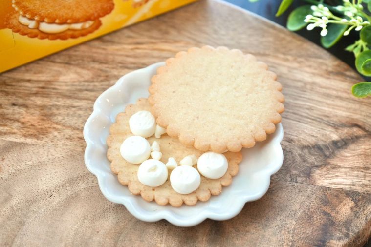 木のカッティングボードと白い皿にのったレモン味のビスケットサンドの中身