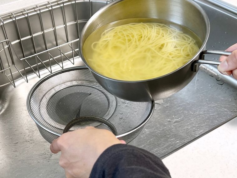 パスタをザルで湯切りしようとしている様子