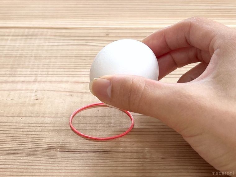 輪ゴムの輪の中に卵を置こうとしている様子