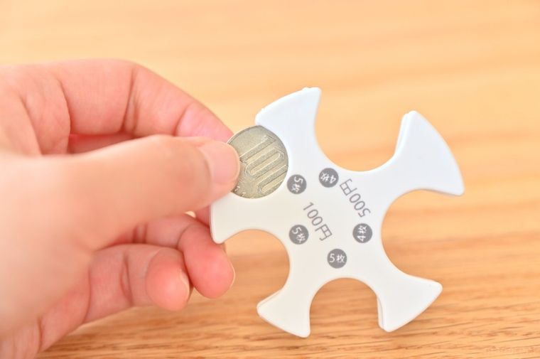 白いコインホルダーに100円玉を入れている