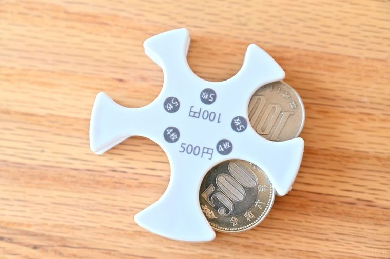 白いコインホルダーに100円玉と500円玉を入れている