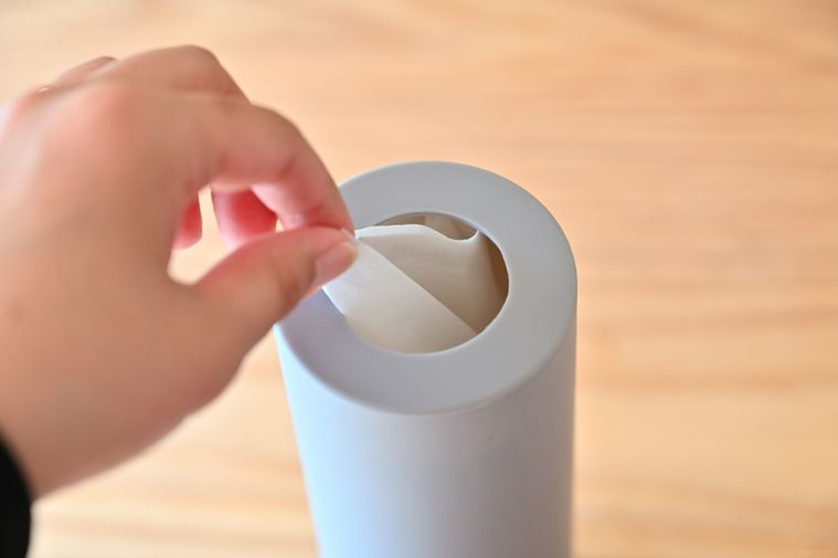 筒状ティッシュケースからティッシュを1枚取り出そうとしている