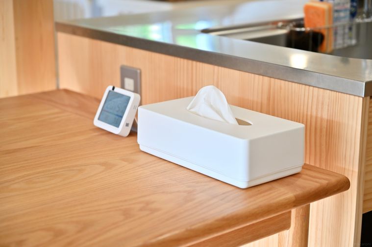 湿度計と白いティッシュケースが並んで木のテーブルに置かれている