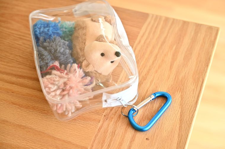 ガチャ詰めポーチにブルーのカラビナを取り付けている