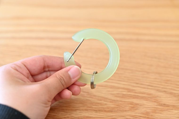 グリーンの丸型カラビナを手に持っている