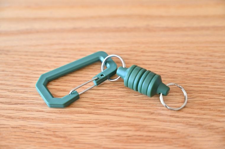 木のテーブルに置いたグリーンのマグネット付きカラビナ