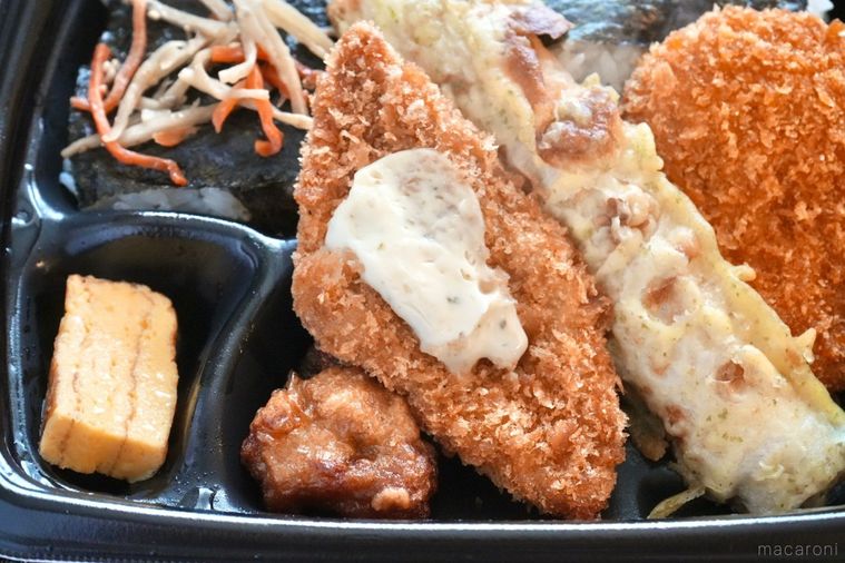 黒い容器に盛られたのり弁当のタルタルソースのせ白身魚のフライのアップとちくわの磯辺揚げと唐揚げ