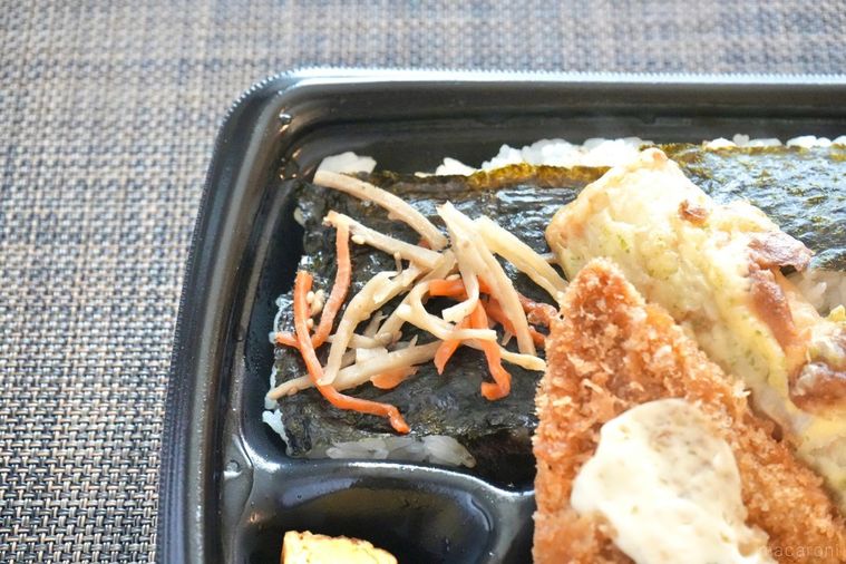 黒い容器に盛られたのり弁のごはんの上のきんぴらごぼうのアップ