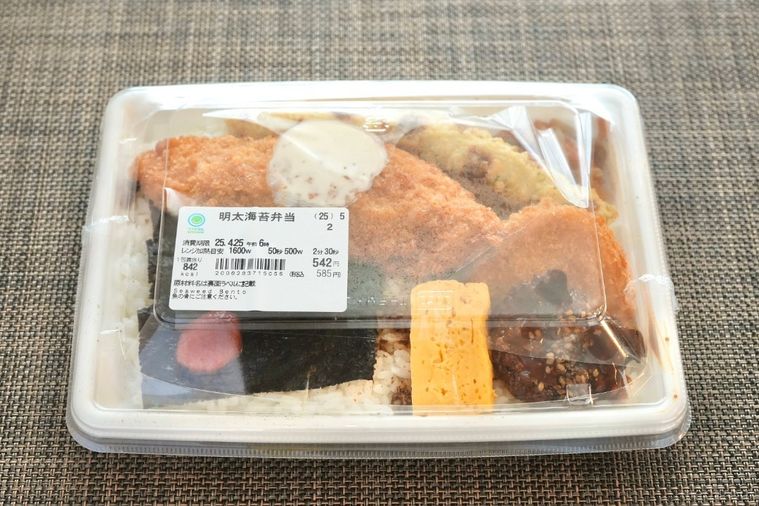 茶色いランチョンマットと白い容器に盛られた白身魚のフライ含む6種類のおかずがのせのり弁当