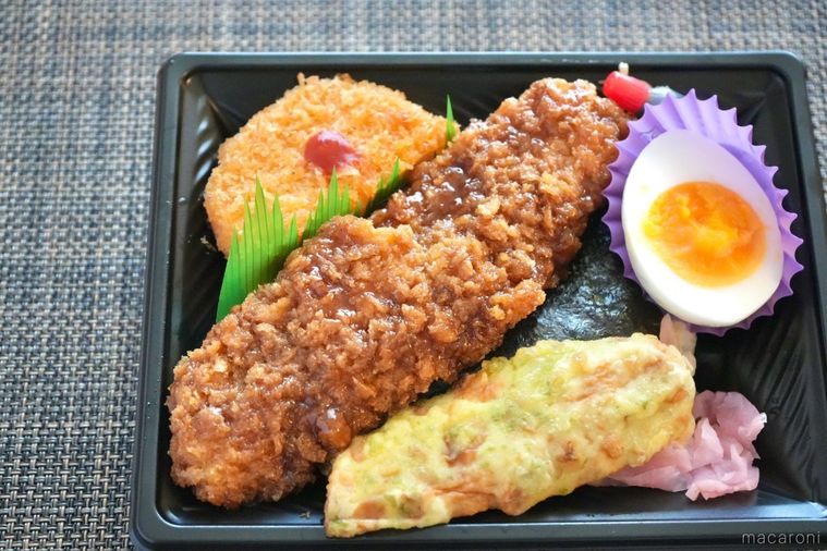 茶色いランチョンマットの上のイカフライとちくわの磯辺揚げとコロッケとゆで卵のせのり弁当