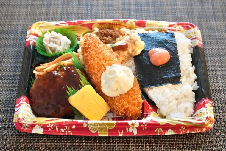 茶色いランチョンマットの上の白身魚のフライのせのり弁当とおかず