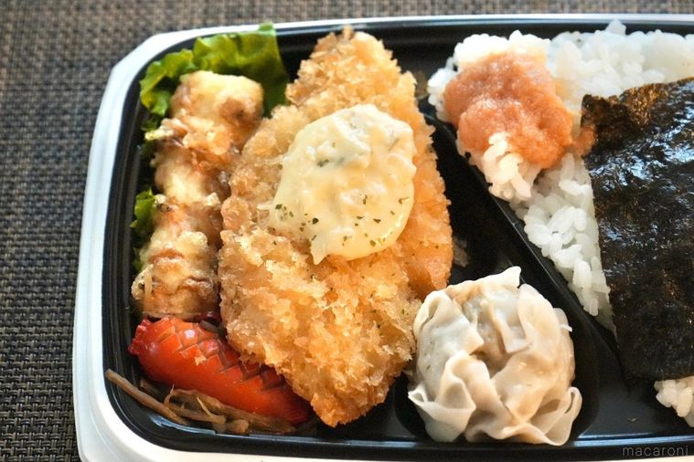 茶色いランチョンマットの上の白身魚のフライのせのり弁当とちくわ天と焼売とウインナー