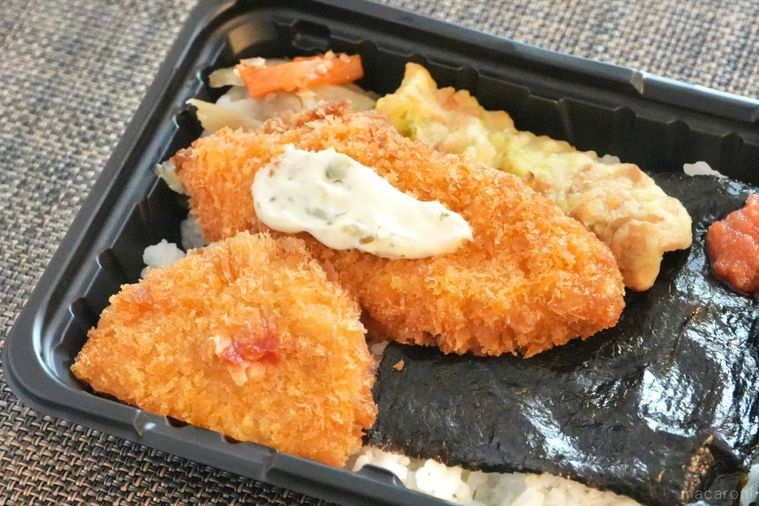 茶色いランチョンマットの上の白身魚のフライのせのり弁当とちくわの磯辺揚げとハーフコロッケときんぴらごぼう