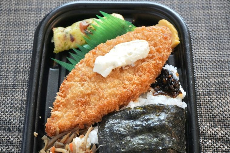 茶色いランチョンマットの上の白身魚のフライとちくわの磯辺揚げときんぴらごぼうのせのり弁当