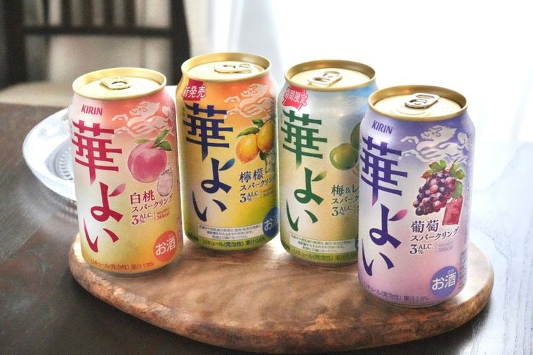 木のカッティングボードにのった白桃とレモンと梅とぶどうのカラフルなフルーツ缶チューハイ