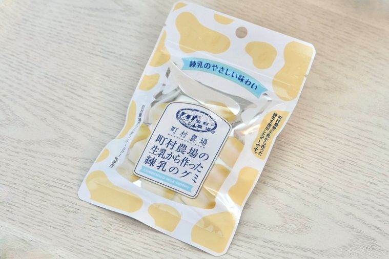 白い木目のテーブルと牛乳瓶をイメージしたグミの白とクリーム色のパッケージ