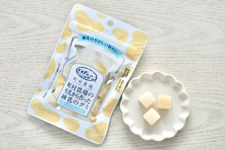 白い木目のテーブルと白い小皿にのった乳白色のキューブ状のグミ