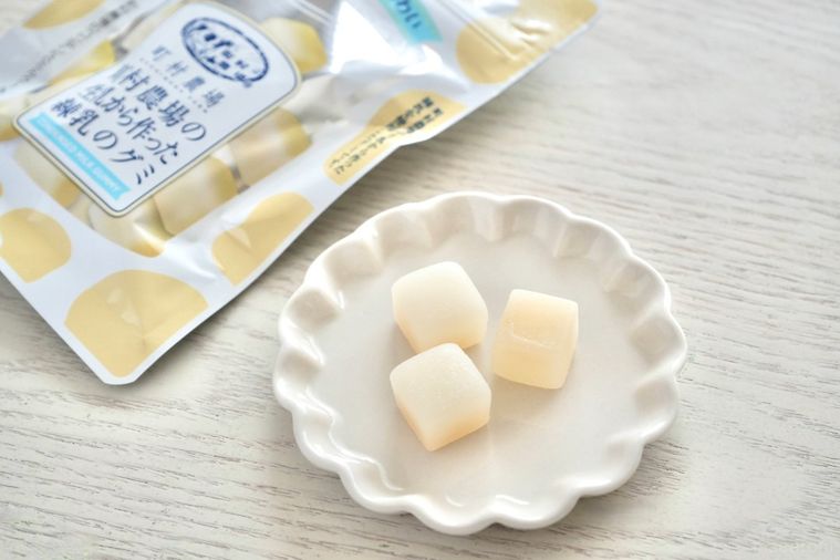 白い木目のテーブルと白い小皿にのった乳白色のキューブ状のグミ