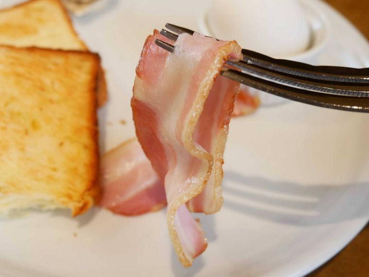 モーニングプレートのベーコンをフォークで持ち上げている様子