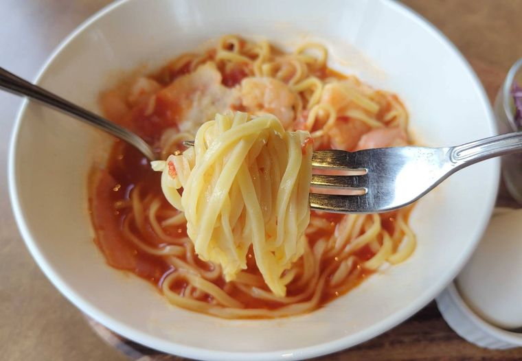 トマトスープパスタの生麵を持ち上げている様子