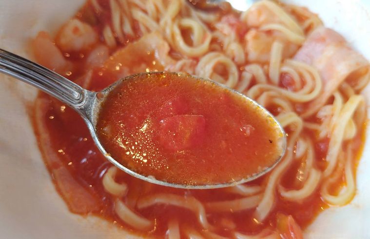 スプーンですくった、トマトスープパスタのスープ