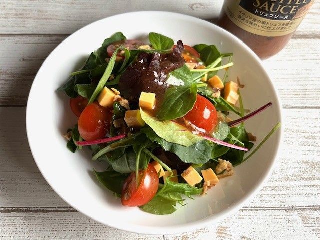 トリュフソースをかけてあるベビーリーフ、プチトマト、チーズのサラダ