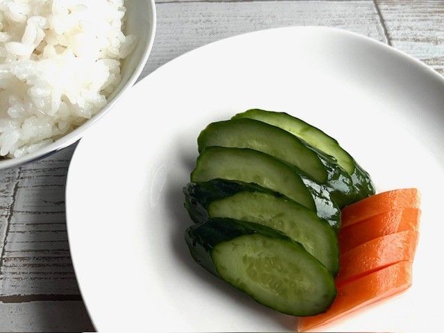 テーブルにごはんときゅうり、にんじんの浅漬けが置かれている