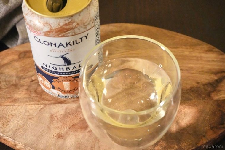 木のカッティングボードにのったアイリッシュウイスキーのハイボール缶と注いだグラスとグレーの布