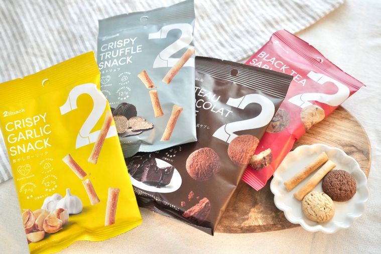 白いテーブルクロスとストライプの布と木のカッティングボードと白い小皿にのったギルトフリーのスナックとサブレ