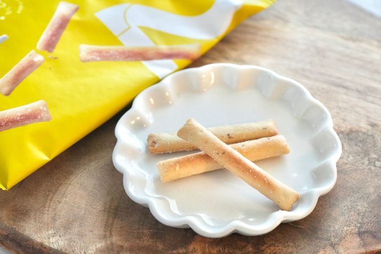 白いテーブルクロスとストライプの布と木のカッティングボードと白い小皿にのったギルトフリーのスナック