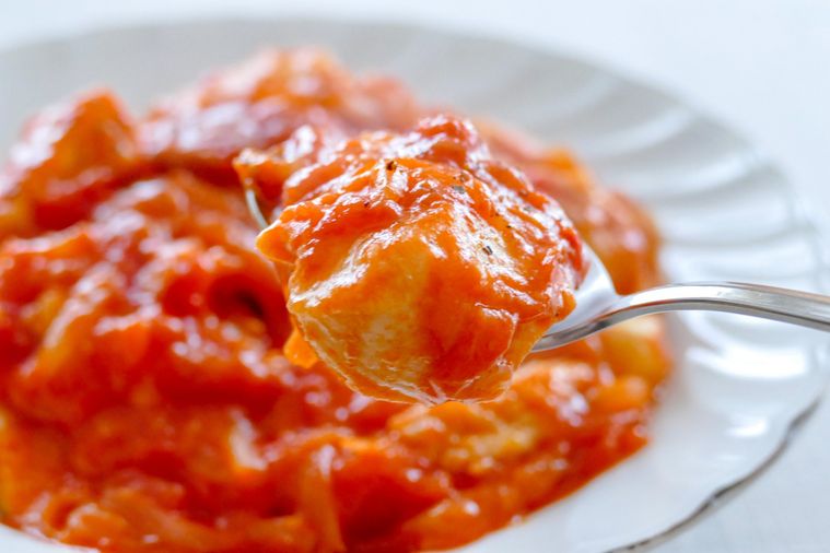 鶏むね肉のトマト煮込みをスプーンですくい上げる様子
