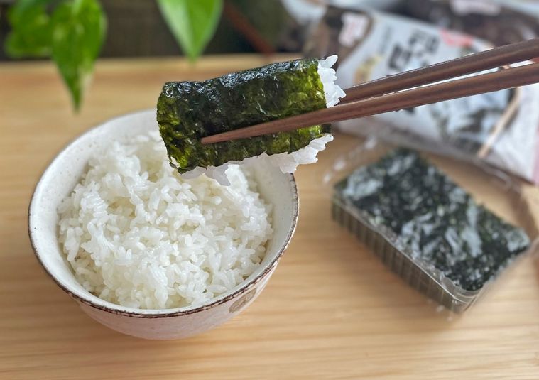 韓国のりで巻いた白米を箸で持っているところ
