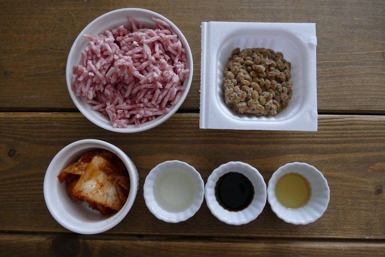 ひき肉と納豆のキムチ炒めの材料が並ぶ木製テーブル
