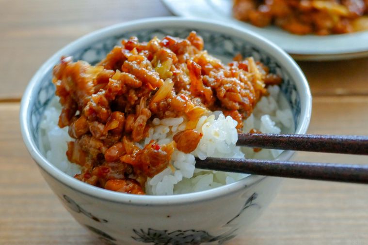 ひき肉と納豆のキムチ炒めをのせた白ごはんを箸で持ち上げる様子