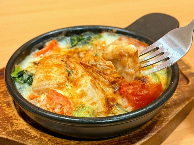 たけのことチキンのミートグラタンのチキンをフォークで持っている様子