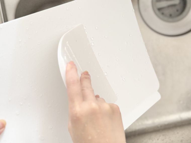 セリア万能タイプのスクレーパーでまな板の水気を切っている様子