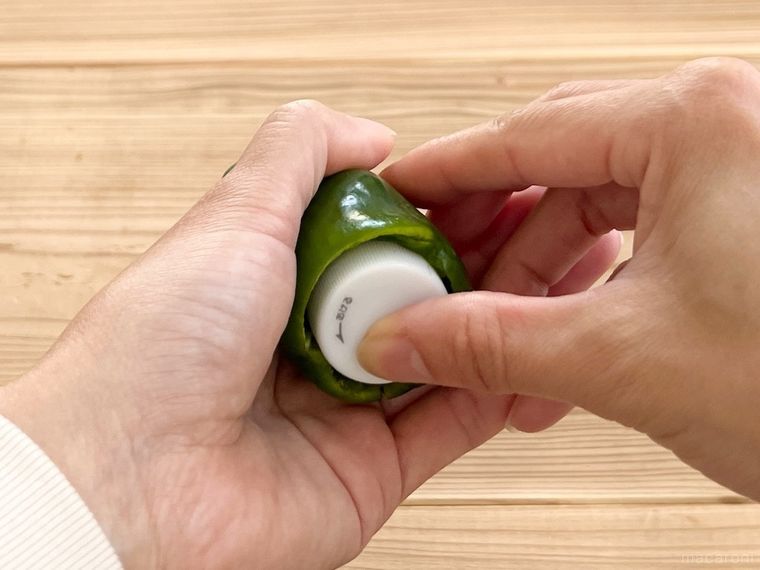 ペットボトルのキャップをピーマンに押し込んでいる様子