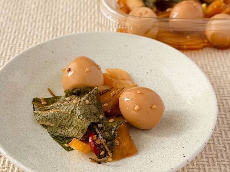 白皿に盛り付けられたうずら卵とえごまの醤油漬とパッケージが並んでいる様子