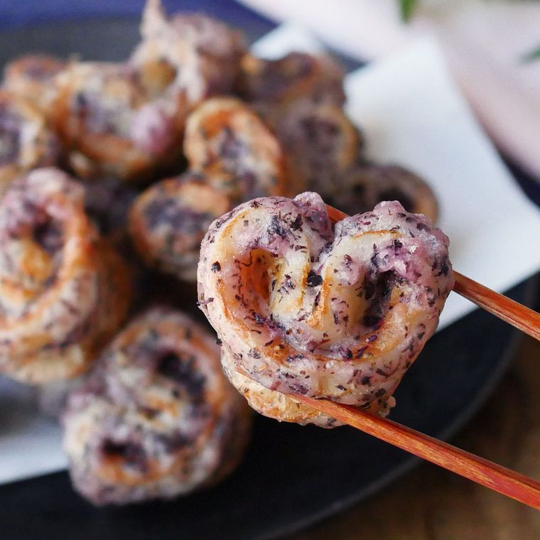 ゆかり衣がついているハート形のちくわの天ぷらを箸で持ち上げる様子